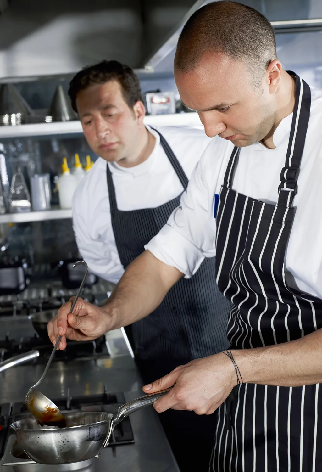 Zwei Männer in der Küche mit Topf und Kelle