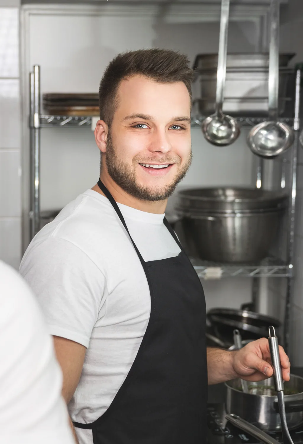 Junger Mann mit Schürze in der Küche